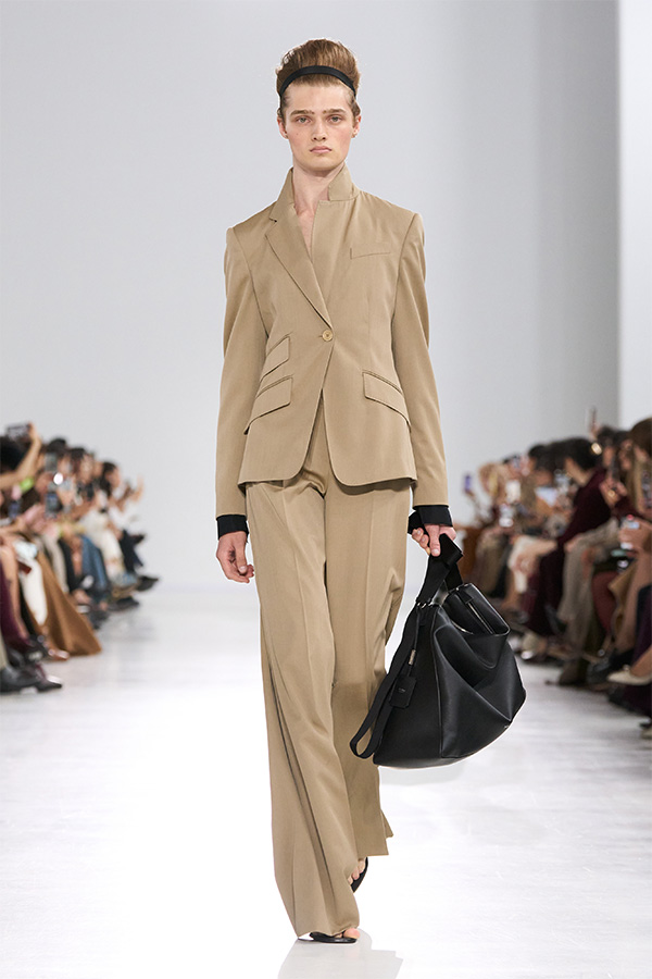 Max Mara Spring/Summer 2026 Fashion Show - Beige Look with plain suit and trousers with black bag held in the hand.